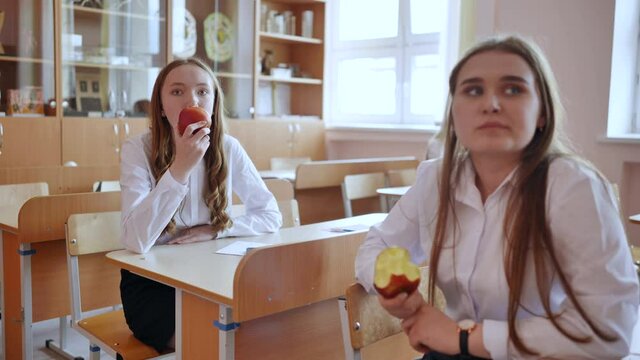 Girls eat apples in class during recess.