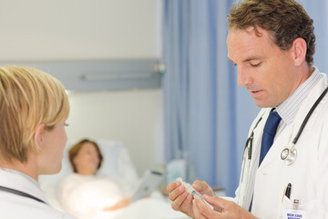 Fototapeta premium Doctor checking syringe in hospital room