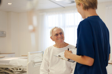 Obraz premium Nurse and older patient talking in hospital room