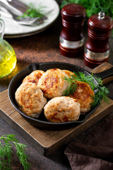 Turkey meat cutlets in a black frying pan on a brown cooking table close-up	