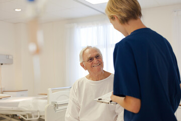 Nurse and older patient talking in hospital room