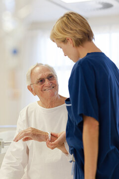 Nurse reading older patient's medical bracelet in hospital