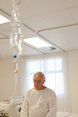 Fototapeta premium Older patient wearing gown in hospital room