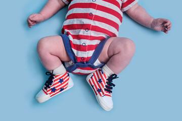 A newborn baby dressed in the colors of the American flag of the United States, blue studio background. A child in the clothes of the red and white USA flag