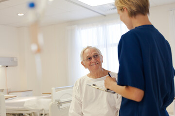 Obraz premium Nurse and older patient talking in hospital room