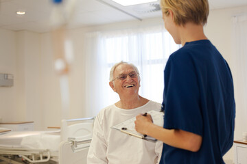 Nurse and older patient talking in hospital room