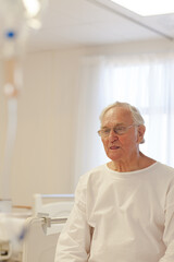 Older patient wearing gown in hospital room