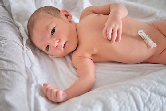 A newborn baby in a diaper is lying naked on the bed. Child boy in a cocoon on a cot.