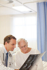 Obraz premium Doctor showing x-rays to older patient in hospital room