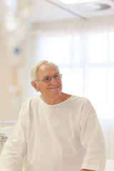 Older patient wearing gown in hospital room