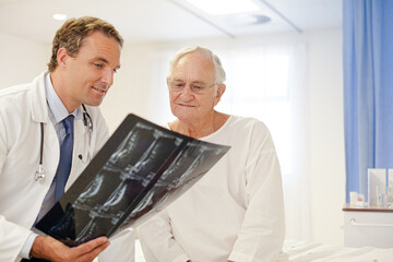 Doctor showing x-rays to older patient in hospital room