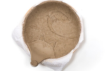 Creative handmade clay products on a shelf in a pottery workshop. Product without glazing and before firing in the oven.