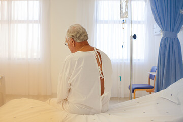 Older patient wearing gown in hospital room