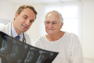 Doctor showing x-rays to older patient in hospital room