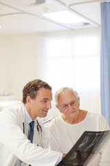 Fototapeta premium Doctor showing x-rays to older patient in hospital room