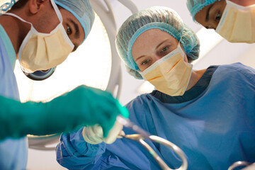 Surgeons bent over patient on operating table - obrazy, fototapety, plakaty