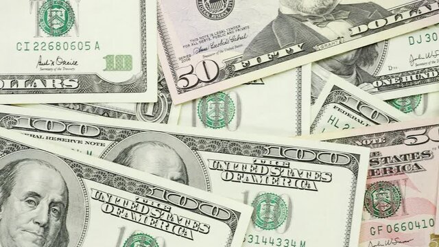 A money pile of various US banknotes in 4K VIDEO. Cash of dollar bills, paper currency background.