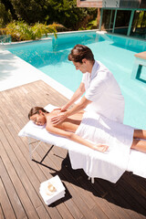 Obraz premium Woman receiving massage poolside at spa
