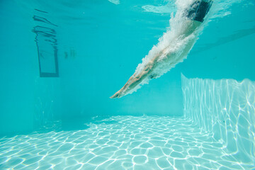 Man swimming underwater in pool