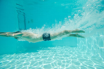 Man swimming underwater in pool - Powered by Adobe