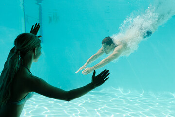 Woman watching boyfriend underwater in swimming pool