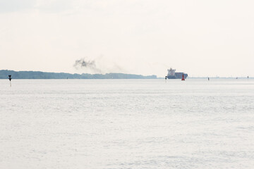 Cargo container ship departing from the port to the sea in the mist