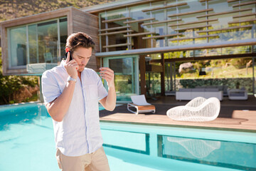 Man talking on cell phone at poolside