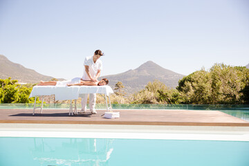 Woman receiving massage poolside at spa