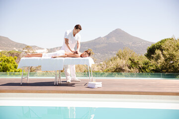 Woman receiving massage poolside at spa
