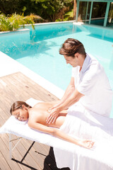Woman receiving massage poolside at spa
