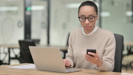 African Businesswoman with Laptop using Smartphone 