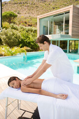 Obraz na płótnie Canvas Woman receiving massage poolside at spa