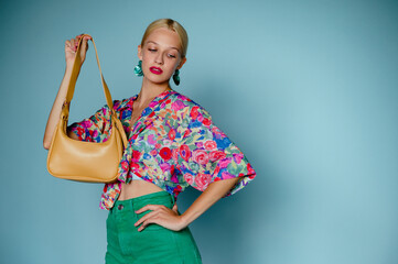 Summer fashion studio portrait of stylish woman wearing trendy colorful blouse, green jeans,...