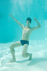 Man posing underwater in swimming pool