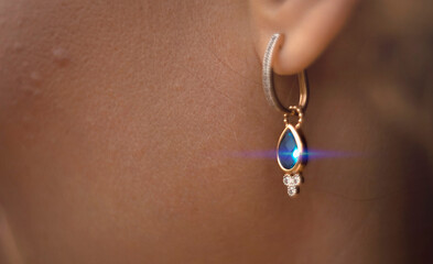 Earring with a blue stone in the ear of a girl close-up