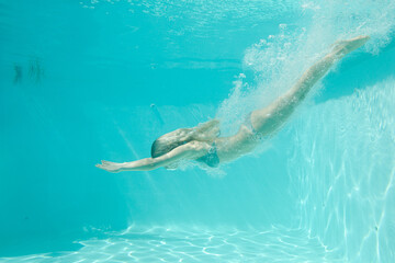 Obraz na płótnie Canvas Woman swimming underwater in pool