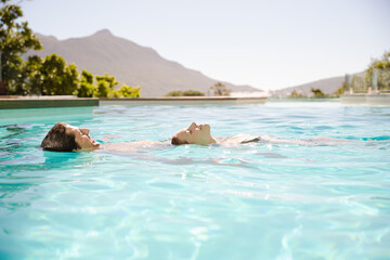 Fototapeta premium Couple floating in swimming pool