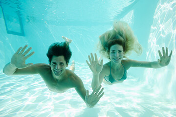 Smiling couple underwater in pool