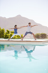 Man and woman practicing yoga at poolside
