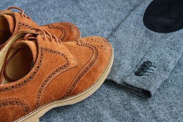 A pair of brown suede derby shoes on tweed blazer background. Top view.