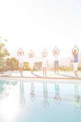 People practicing yoga at poolside