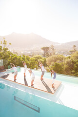 Obraz premium People practicing yoga at poolside