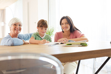Obraz premium Mother and grandmother helping girl with homework
