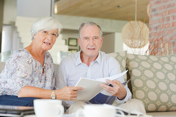 Couple examining blueprints on sofa