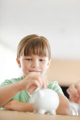 Girl filling piggy bank on counter