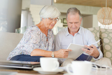 Couple examining blueprints on sofa