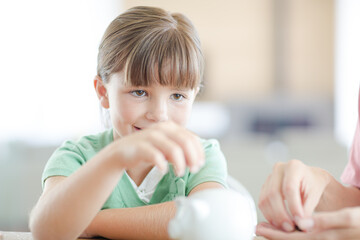 Girl filling piggy bank on counter