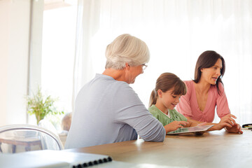 Obraz premium Three generations of women using tablet computer