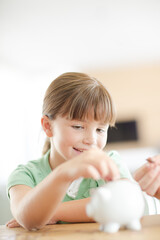 Girl filling piggy bank on counter