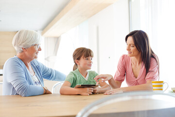 Obraz premium Three generations of women using tablet computer